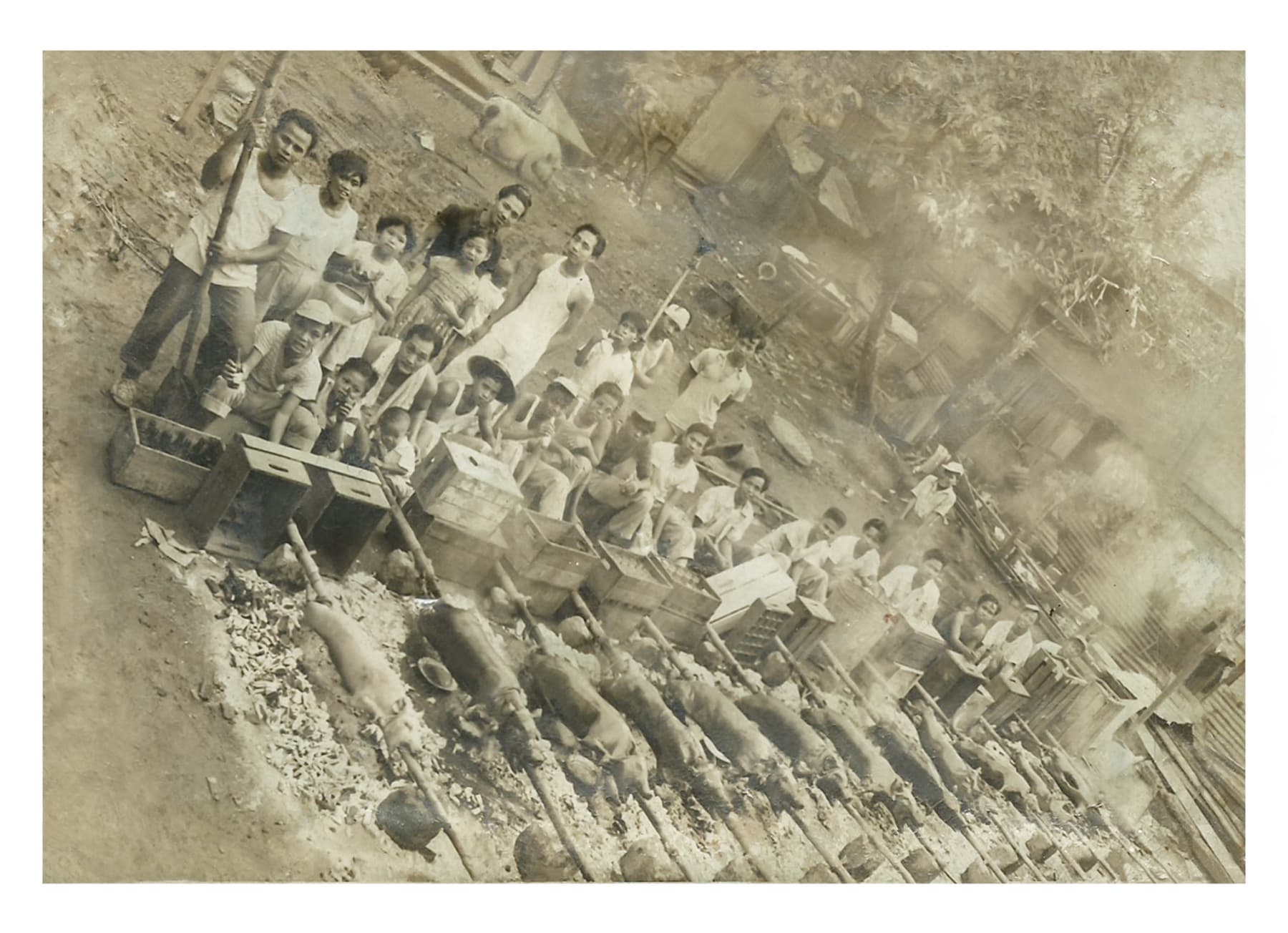Vintage photo of the Leonardo's family roasting rows of lechon over open coals